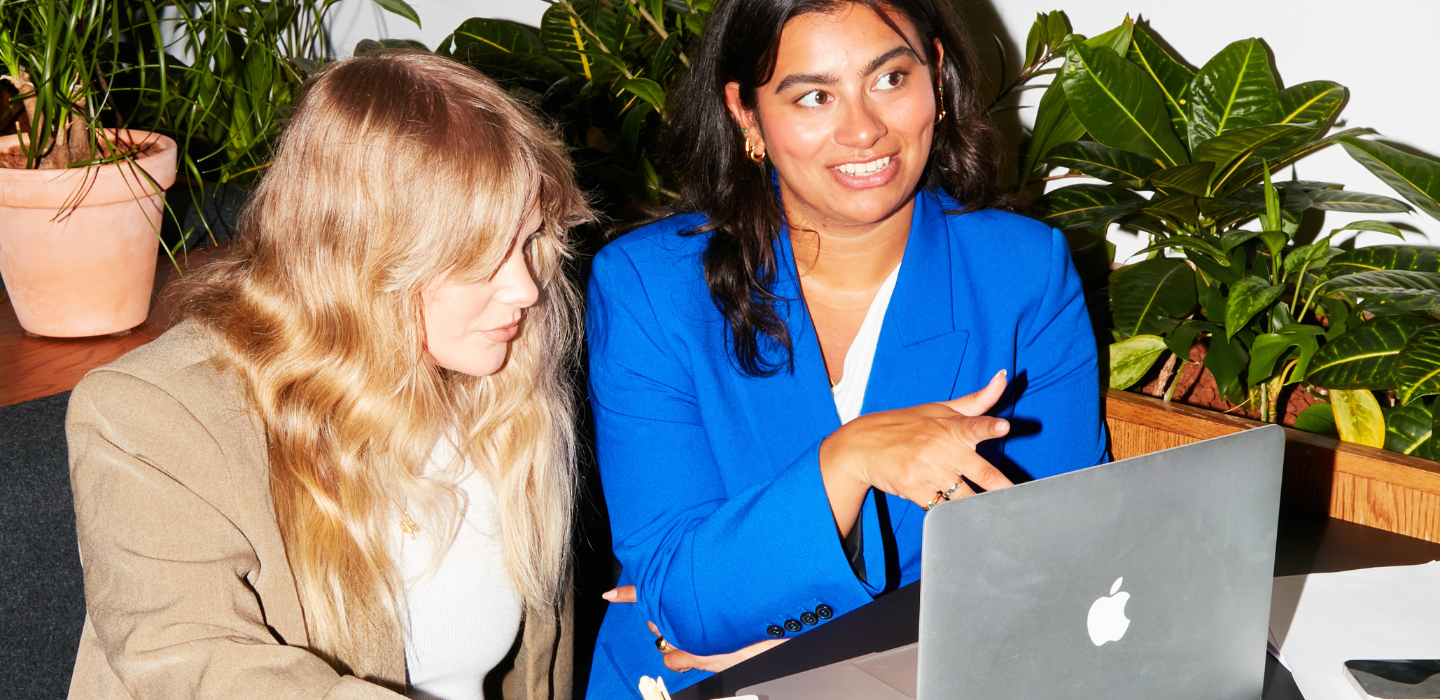 Two women collaborating on a laptop in an office.