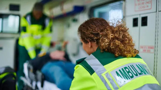 Paramedics assisting a patient in an ambulance.